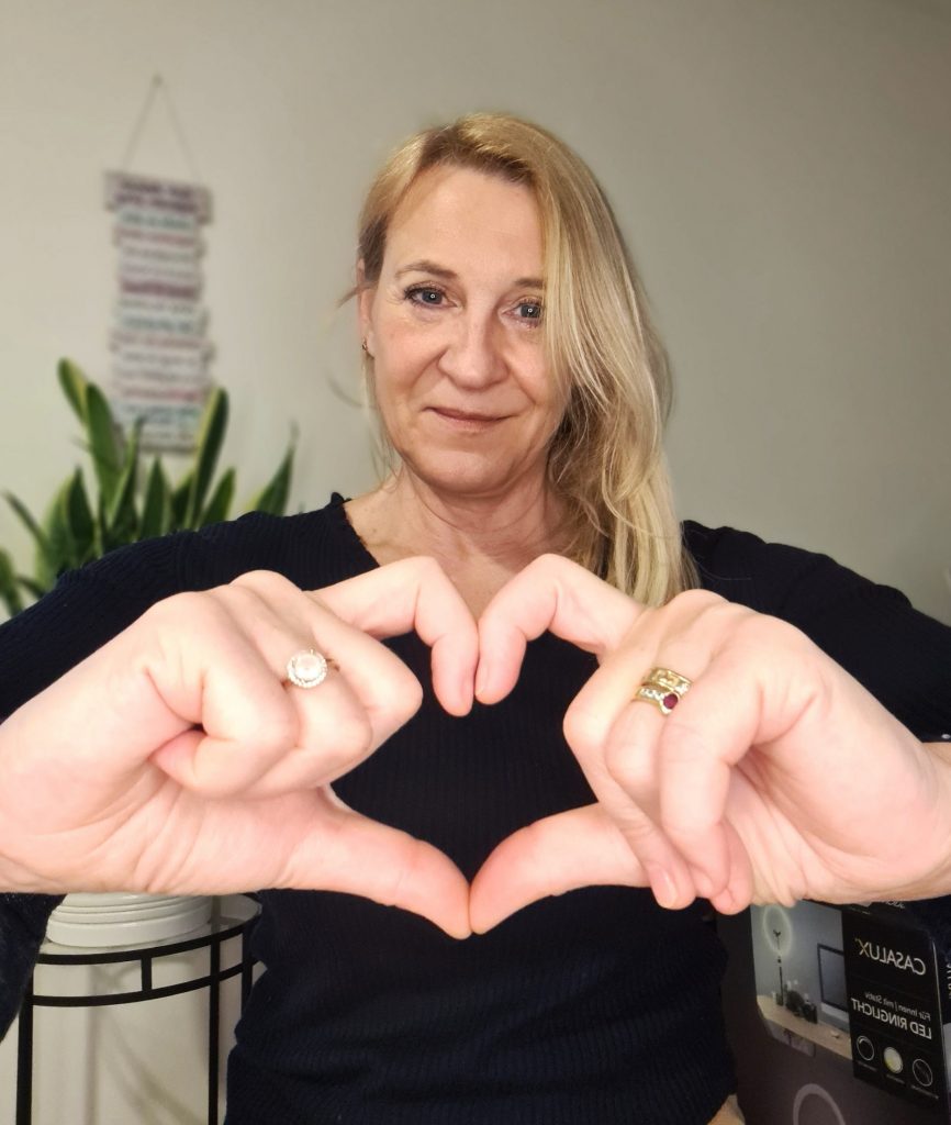Portrait Monica Neuböck, Coach, Sellbstliebe-Trainerin, die eine Herz mit ihren Fingern formt